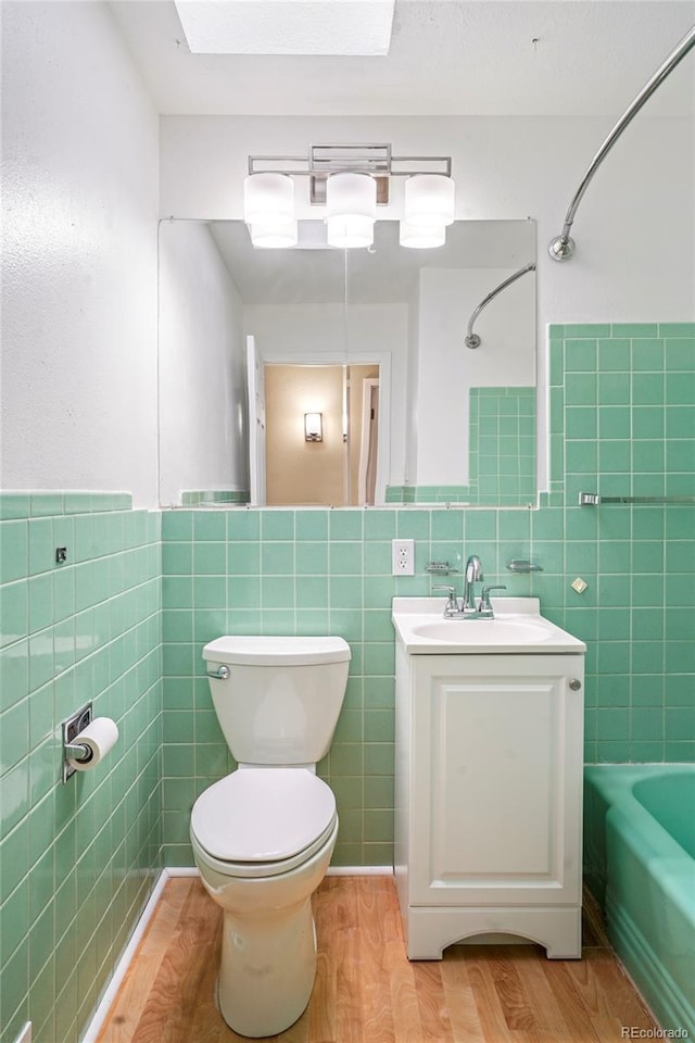 full bathroom featuring shower / bathtub combination, vanity, wood-type flooring, tile walls, and toilet