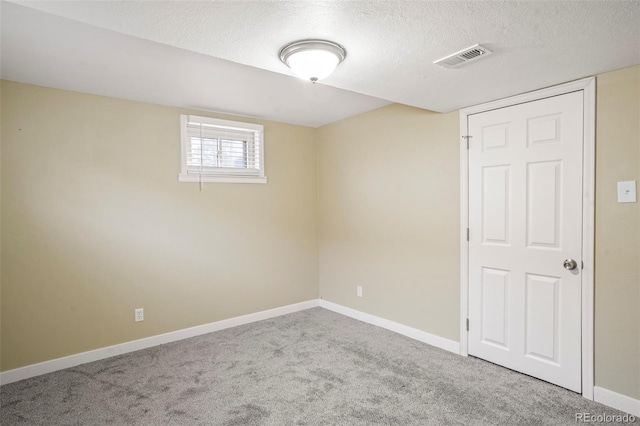 carpeted empty room with a textured ceiling