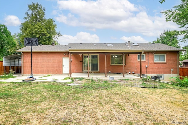 back of house with a lawn, central AC unit, and a carport