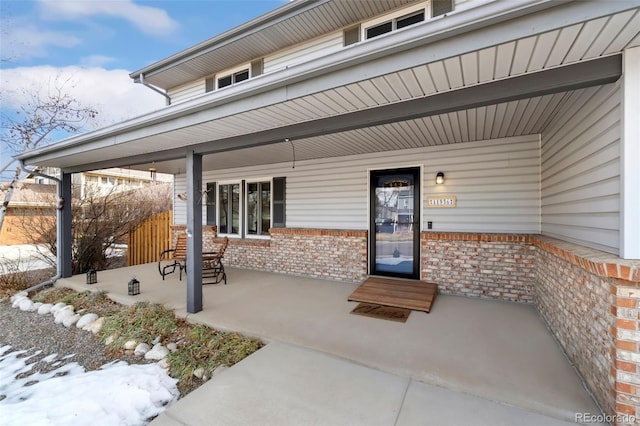 entrance to property with a porch and brick siding