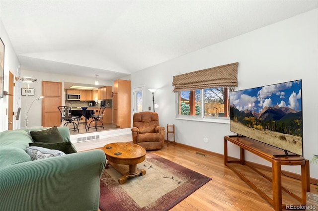 living room featuring lofted ceiling, visible vents, light wood-style flooring, and baseboards