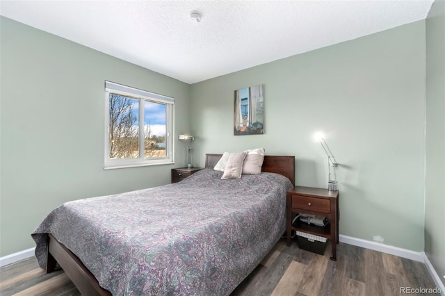 bedroom featuring a textured ceiling, baseboards, and wood finished floors