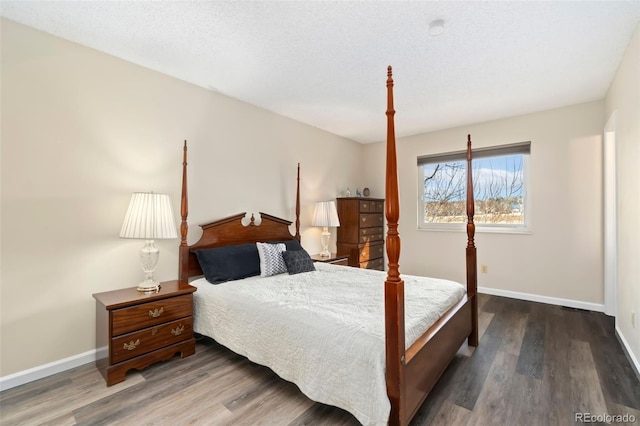 bedroom featuring a textured ceiling, baseboards, and wood finished floors