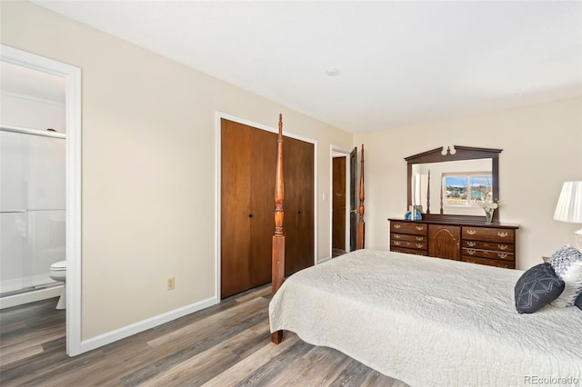 bedroom with ensuite bathroom, baseboard heating, wood finished floors, and baseboards