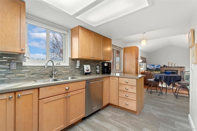 kitchen featuring a peninsula, a fireplace, a sink, open floor plan, and dishwasher