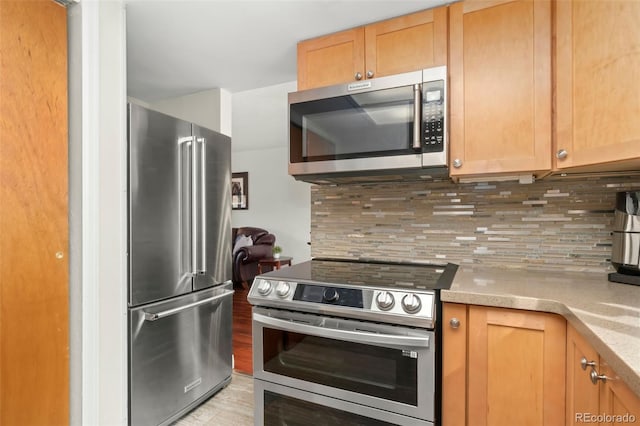 kitchen featuring light countertops, appliances with stainless steel finishes, backsplash, and light wood-style flooring