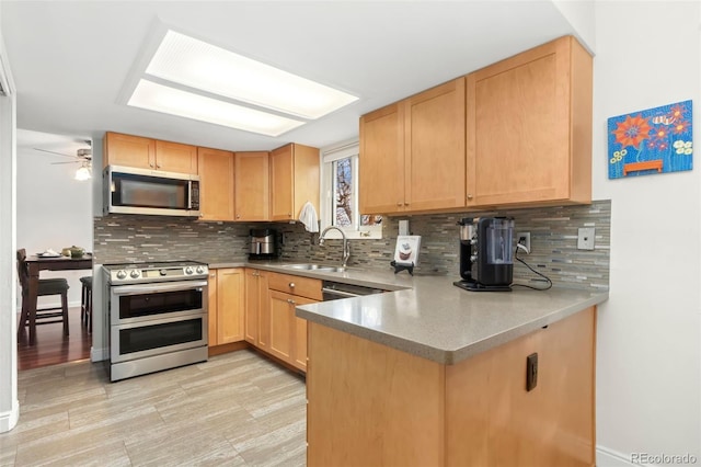 kitchen with appliances with stainless steel finishes, light brown cabinets, a sink, and decorative backsplash