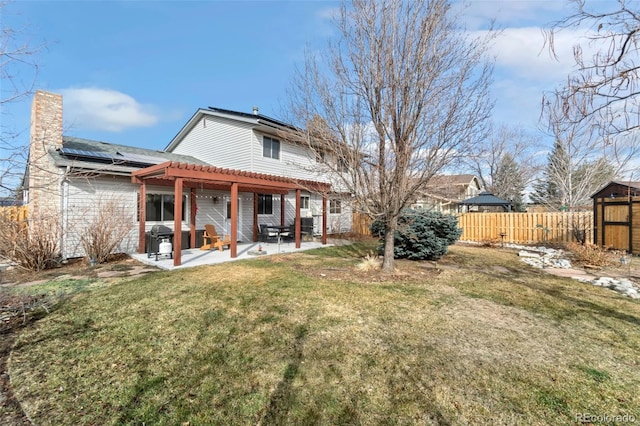 back of house featuring a lawn, a patio, a chimney, fence, and a pergola