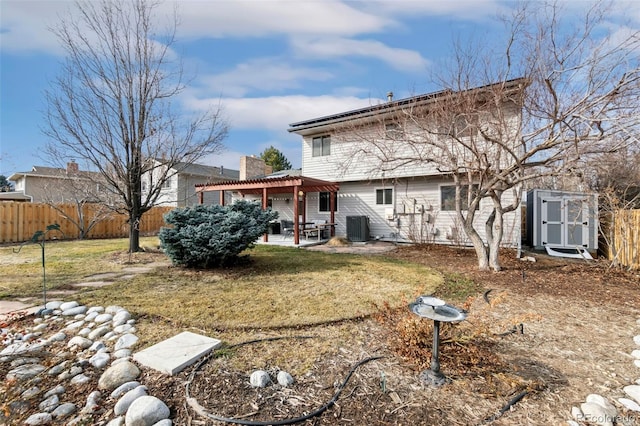 rear view of house with a patio, central AC, fence, a lawn, and a pergola