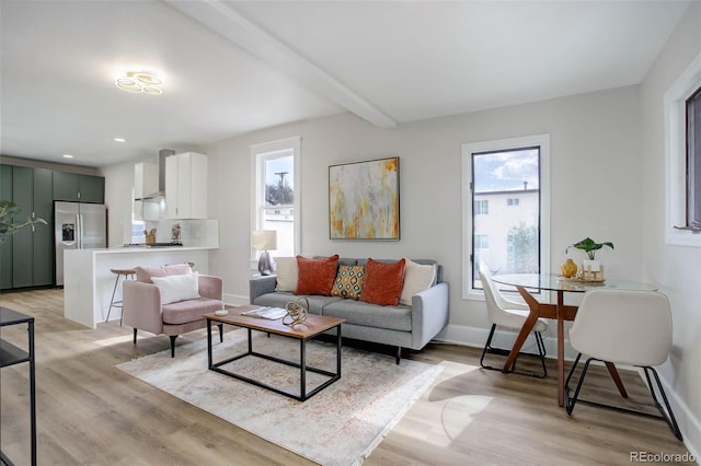 living room with beamed ceiling, light hardwood / wood-style flooring, and a healthy amount of sunlight