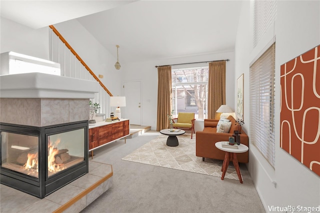 sitting room featuring light carpet, stairs, a towering ceiling, and a tile fireplace