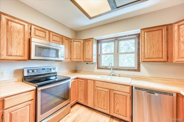 kitchen with light countertops, stainless steel appliances, a sink, and light wood-style floors