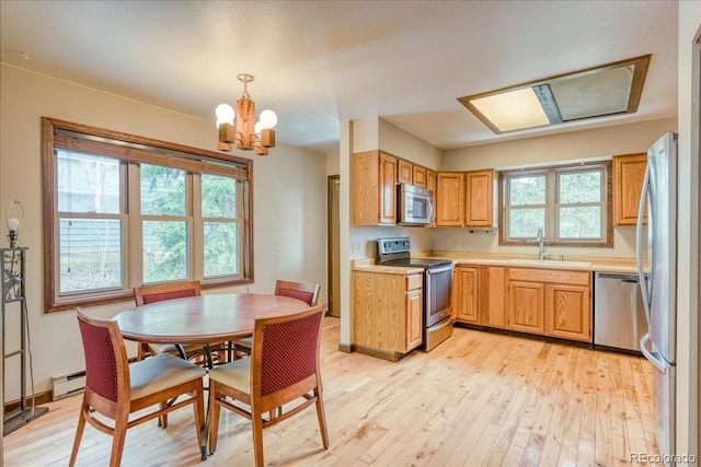 kitchen featuring a sink, baseboard heating, light wood-style floors, a chandelier, and stainless steel appliances