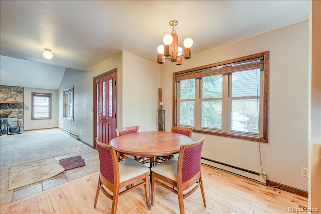 dining area featuring light wood-type flooring, baseboards, a baseboard radiator, lofted ceiling, and an inviting chandelier