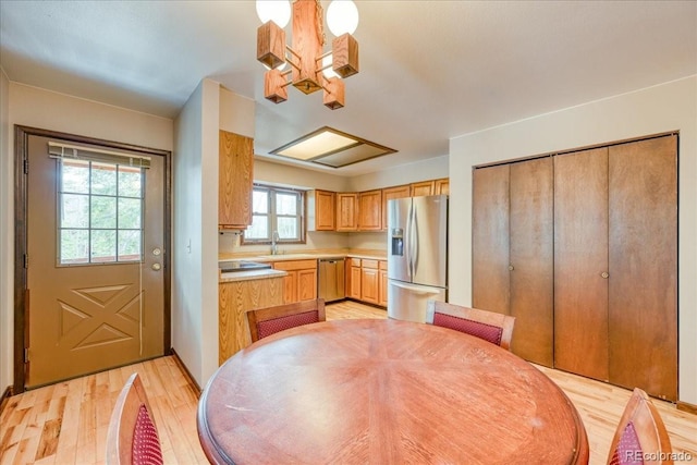 kitchen with an inviting chandelier, light wood-style floors, light countertops, a sink, and appliances with stainless steel finishes