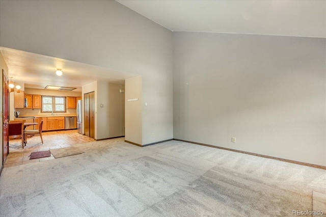 unfurnished living room with a sink, baseboards, and light colored carpet
