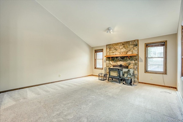 living area featuring carpet flooring, baseboards, a wealth of natural light, and a wood stove