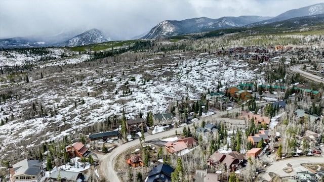 snowy aerial view featuring a mountain view and a residential view