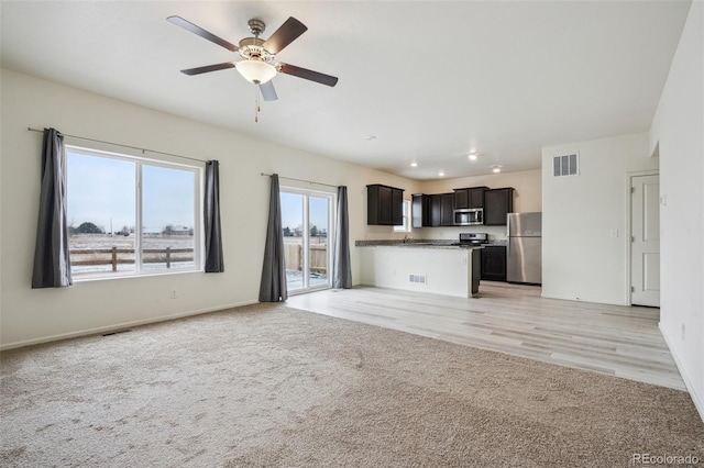 unfurnished living room featuring light colored carpet and ceiling fan