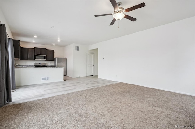 unfurnished living room featuring light colored carpet and ceiling fan