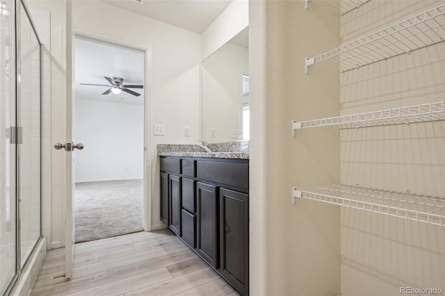 bathroom with hardwood / wood-style flooring, ceiling fan, vanity, and a shower with shower door