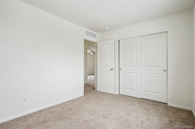 unfurnished bedroom with light colored carpet and a closet