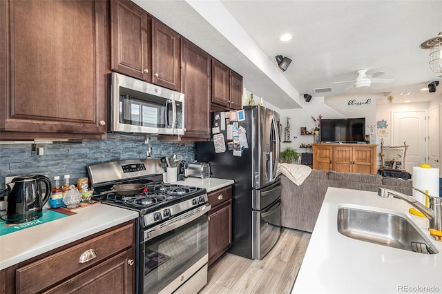 kitchen featuring light hardwood / wood-style floors, ceiling fan, appliances with stainless steel finishes, decorative backsplash, and sink