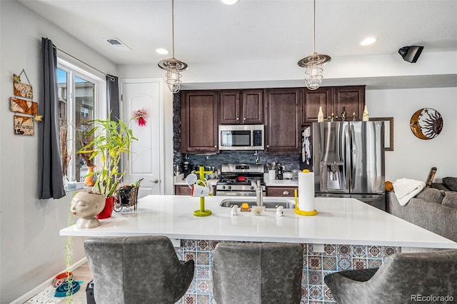 kitchen featuring decorative backsplash, pendant lighting, dark brown cabinetry, and stainless steel appliances