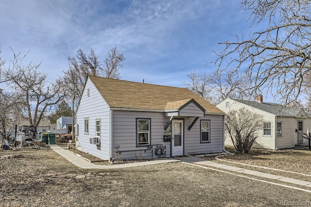 bungalow-style house with cooling unit and roof with shingles