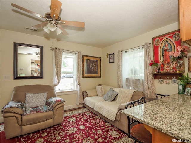 living area with baseboards, visible vents, and a ceiling fan