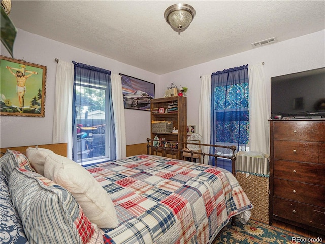 bedroom with a textured ceiling and visible vents