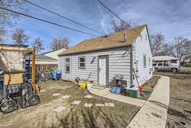 back of house with a shingled roof and fence