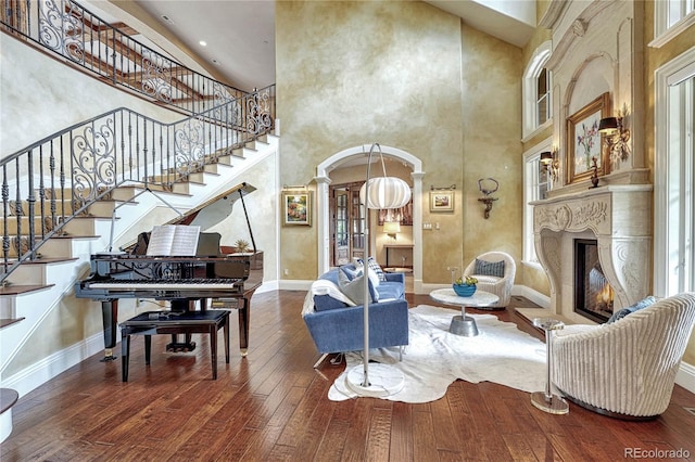 living room with decorative columns, a towering ceiling, and wood-type flooring