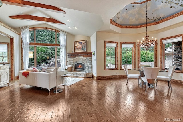 interior space featuring crown molding, high vaulted ceiling, a chandelier, hardwood / wood-style floors, and a stone fireplace