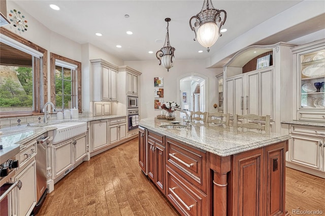 kitchen with appliances with stainless steel finishes, sink, decorative light fixtures, and an island with sink