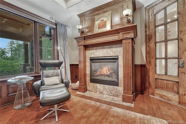 sitting room with a tile fireplace and wood walls