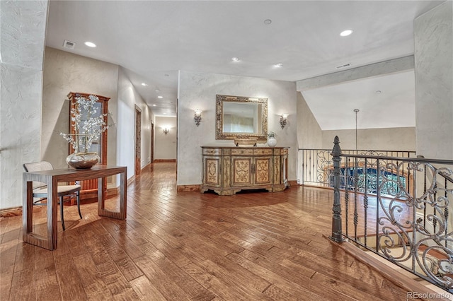 hallway with hardwood / wood-style floors and vaulted ceiling