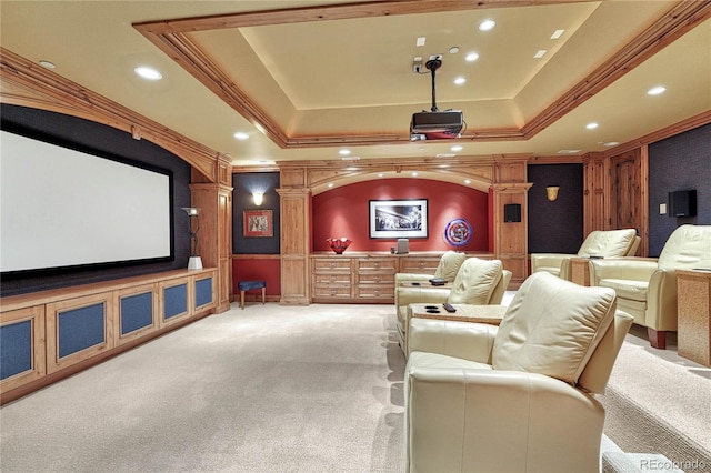 cinema room featuring light carpet, a raised ceiling, ornamental molding, and ornate columns