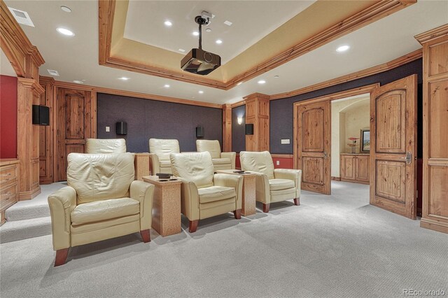 carpeted cinema with a tray ceiling and ornamental molding