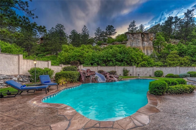 pool at dusk featuring pool water feature