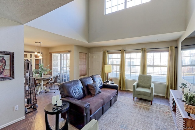 living room featuring hardwood / wood-style flooring, a healthy amount of sunlight, a notable chandelier, and a towering ceiling