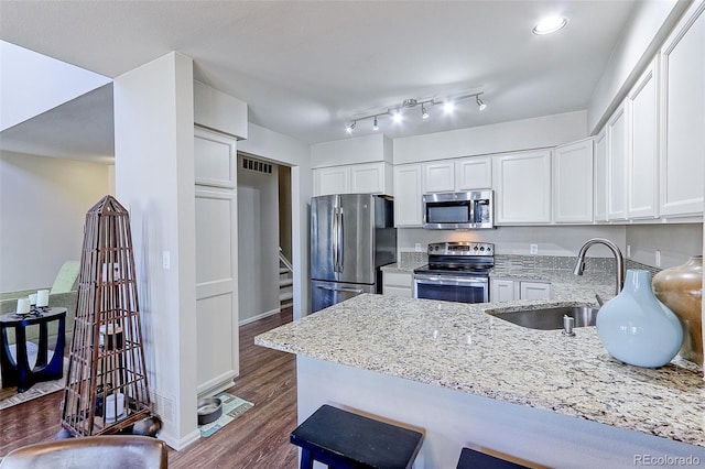 kitchen featuring sink, white cabinets, light stone counters, kitchen peninsula, and stainless steel appliances