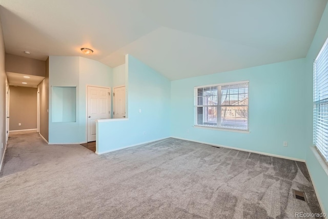 carpeted empty room with lofted ceiling