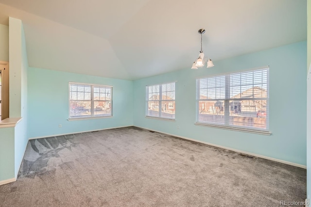 carpeted spare room with vaulted ceiling and a notable chandelier