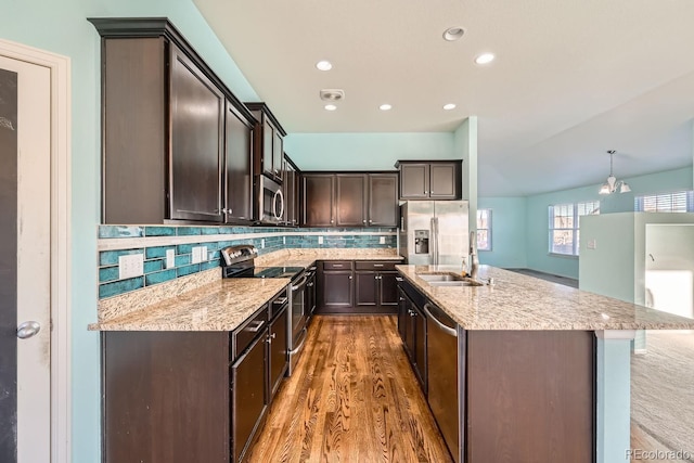 kitchen with decorative backsplash, stainless steel appliances, sink, pendant lighting, and an inviting chandelier