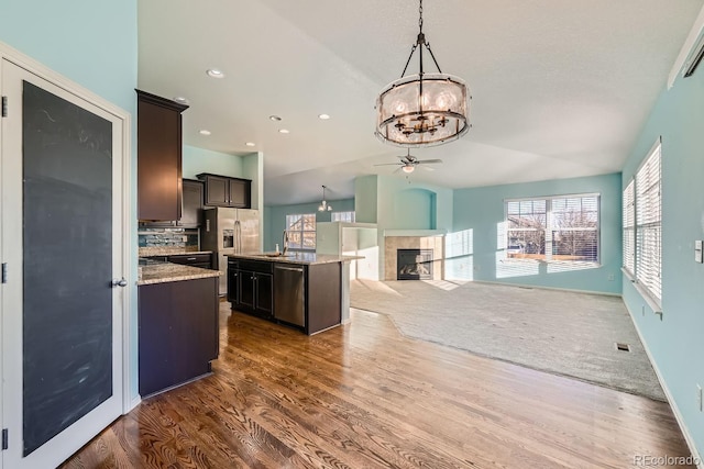 kitchen with dark brown cabinetry, a center island, stainless steel appliances, hanging light fixtures, and dark hardwood / wood-style flooring