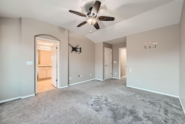 unfurnished bedroom with ceiling fan, light colored carpet, ensuite bathroom, and lofted ceiling