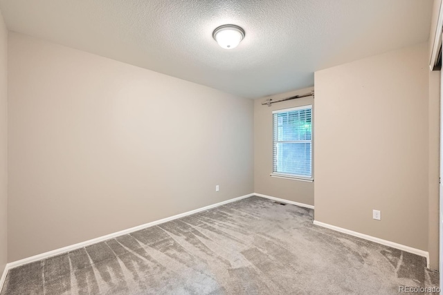 carpeted empty room featuring a textured ceiling