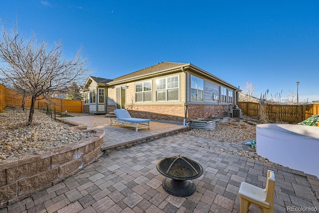 back of property featuring a fire pit, central air condition unit, and a patio