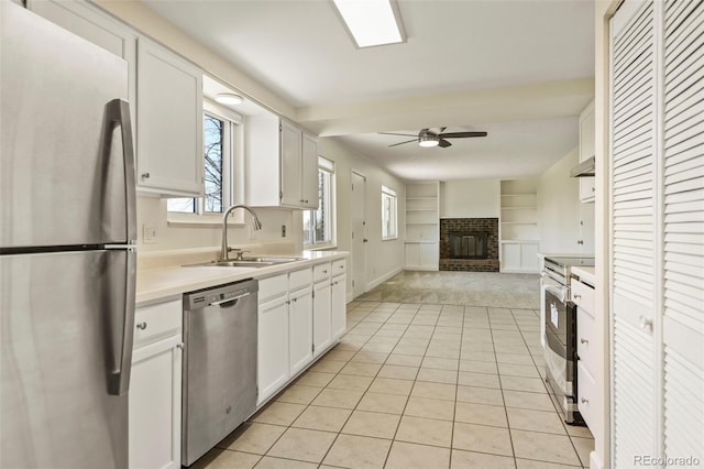9562 W Capri Dr, Littleton, CO 80123 - kitchen featuring a fireplace, a ceiling fan, appliances with stainless steel finishes, light countertops, and a sink